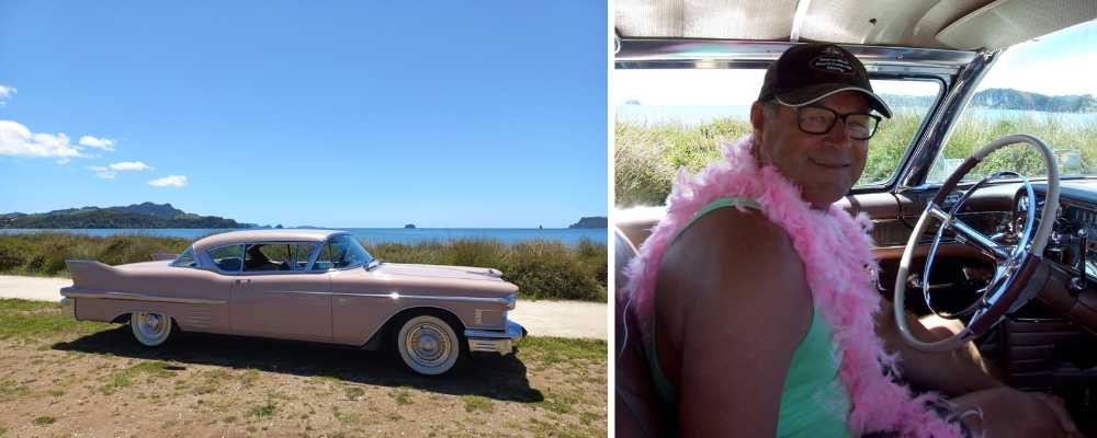 Pink Cadillac parked up by beach and man sitting in car