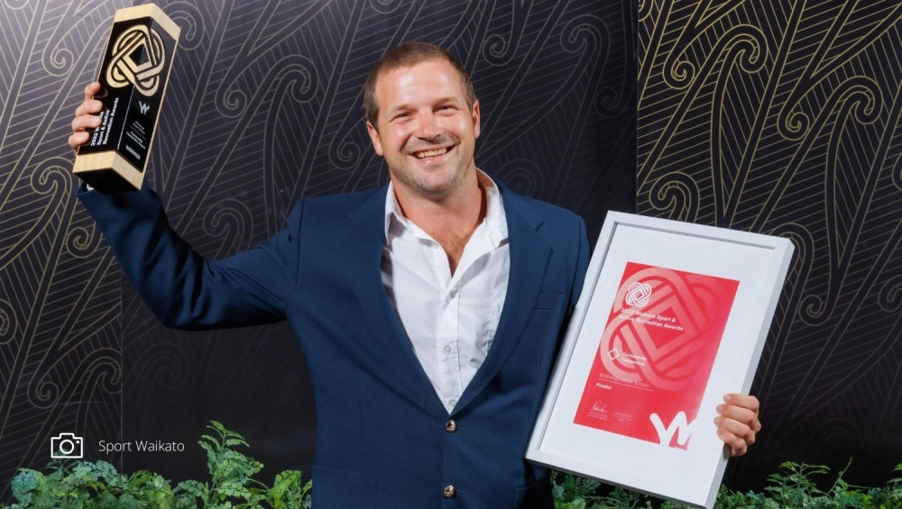man smiling holding award in air