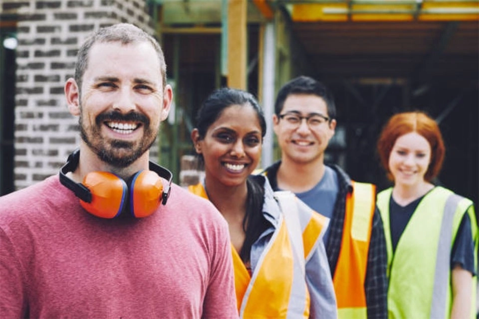 two men and women with high visibility jackets and ear muffs