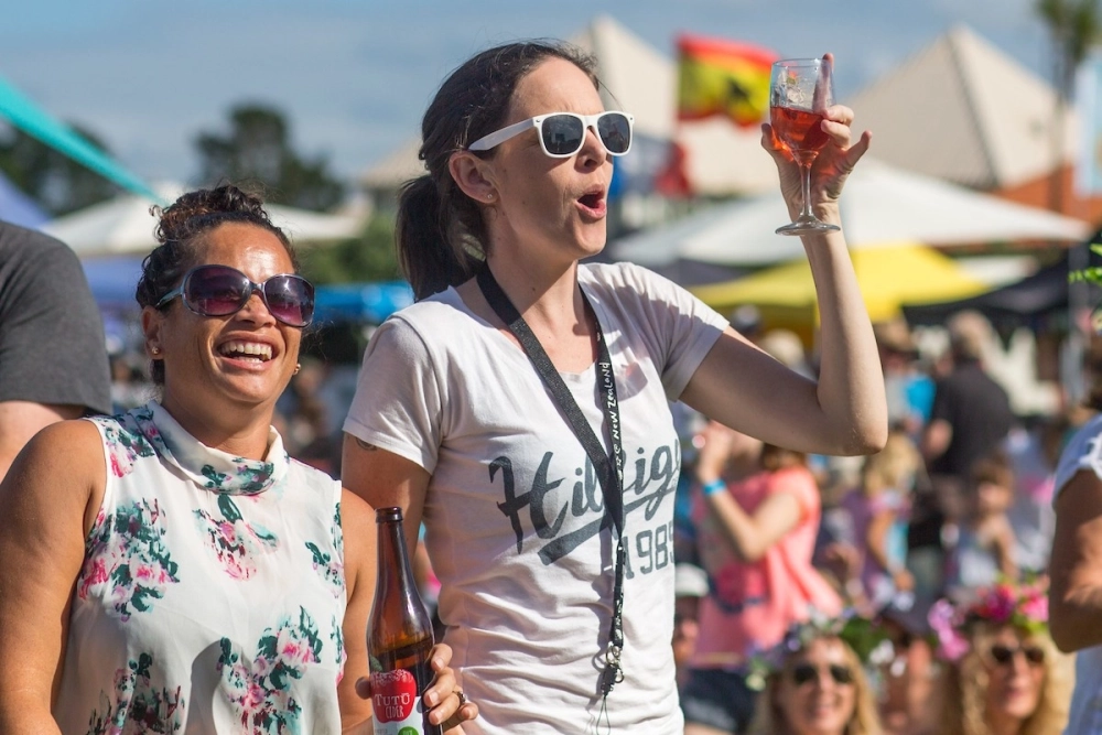 Two women standing up and cheering at a concert