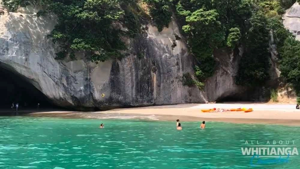 People swimming in sea at beach at Cathedral Cove