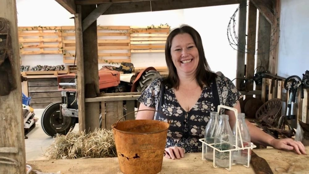 Woman (Lisa Gearon) standing at farm stall