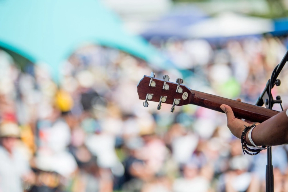 Performer with guitar looking out to crowd at A Taste of Matarangi festival