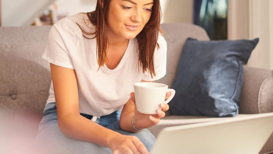 Woman with cup in hand on computer