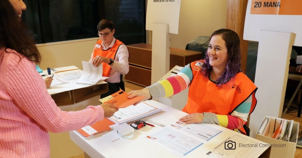 Woman handing out voting paper nz