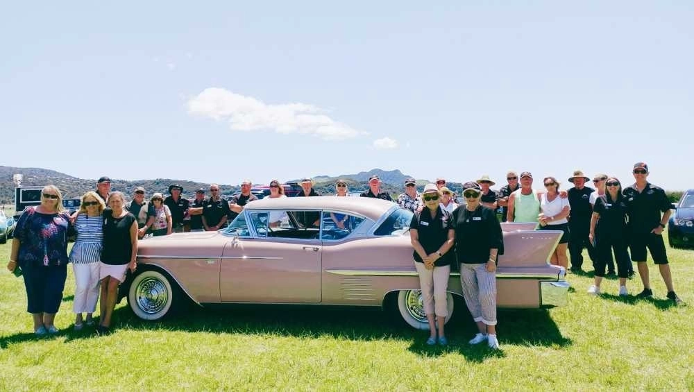 People pictured around pink Cadillac