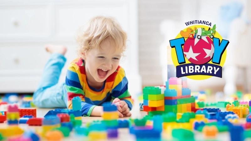 Child lying on stomach playing with coloured plastic blocks