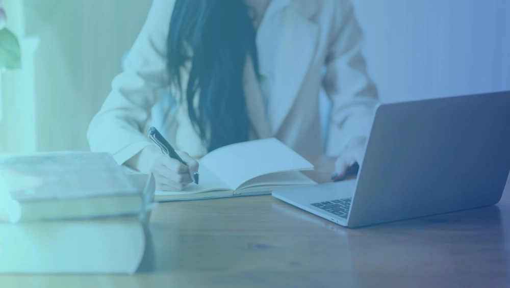 Woman at desk with pen, paper and computer
