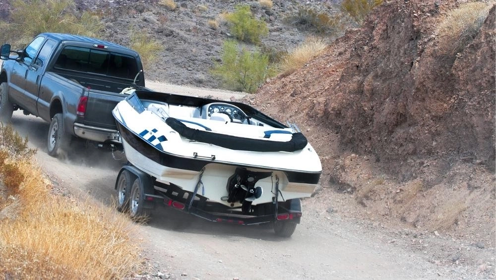 Ute towing boat up gravel road