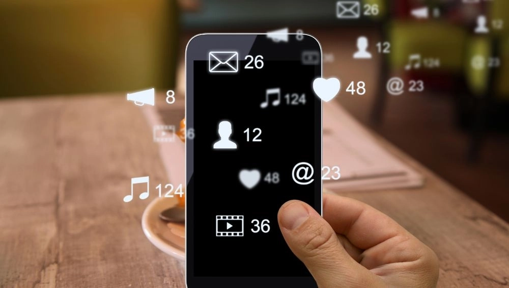 hand holding phone with social icons