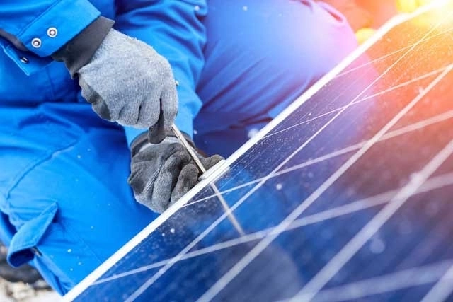 Man in overalls by solar panel
