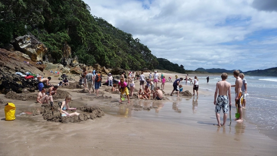 People at Hot Water Beach standing and digging in the sand