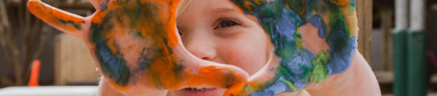 Child looking through painted hands