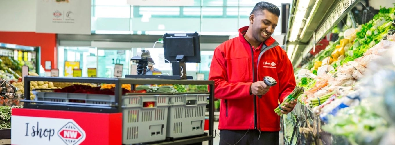 Man in red jacket scanning produce