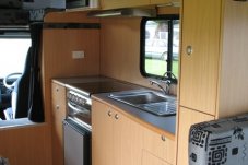 This fully self-contained motorhome kitchen has hot & cold running water, water filter, gas cooking facilities, range hood, fridge and microwave.