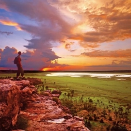 Person standing on cliff at sunset