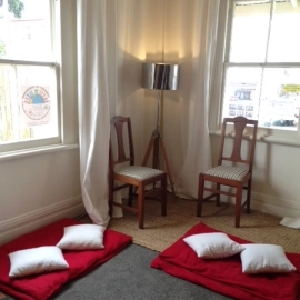 Room with chairs and red rugs and cushions