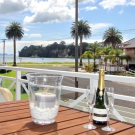 Champagne flutes and bottle on table overlooking beach