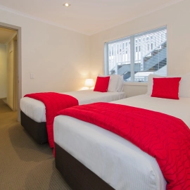 Twin Bedroom with red cushion and blankets