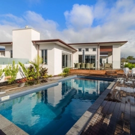 Swimming pool with timber decking next to house