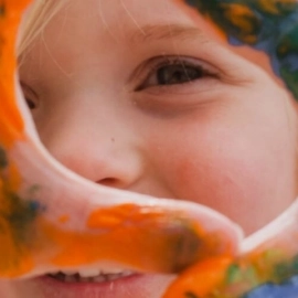 Child looking through painted hands