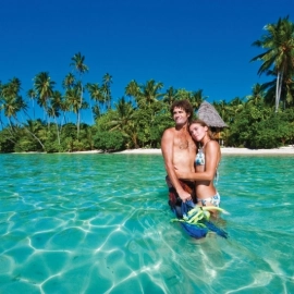 Couple standing in water by tropical island